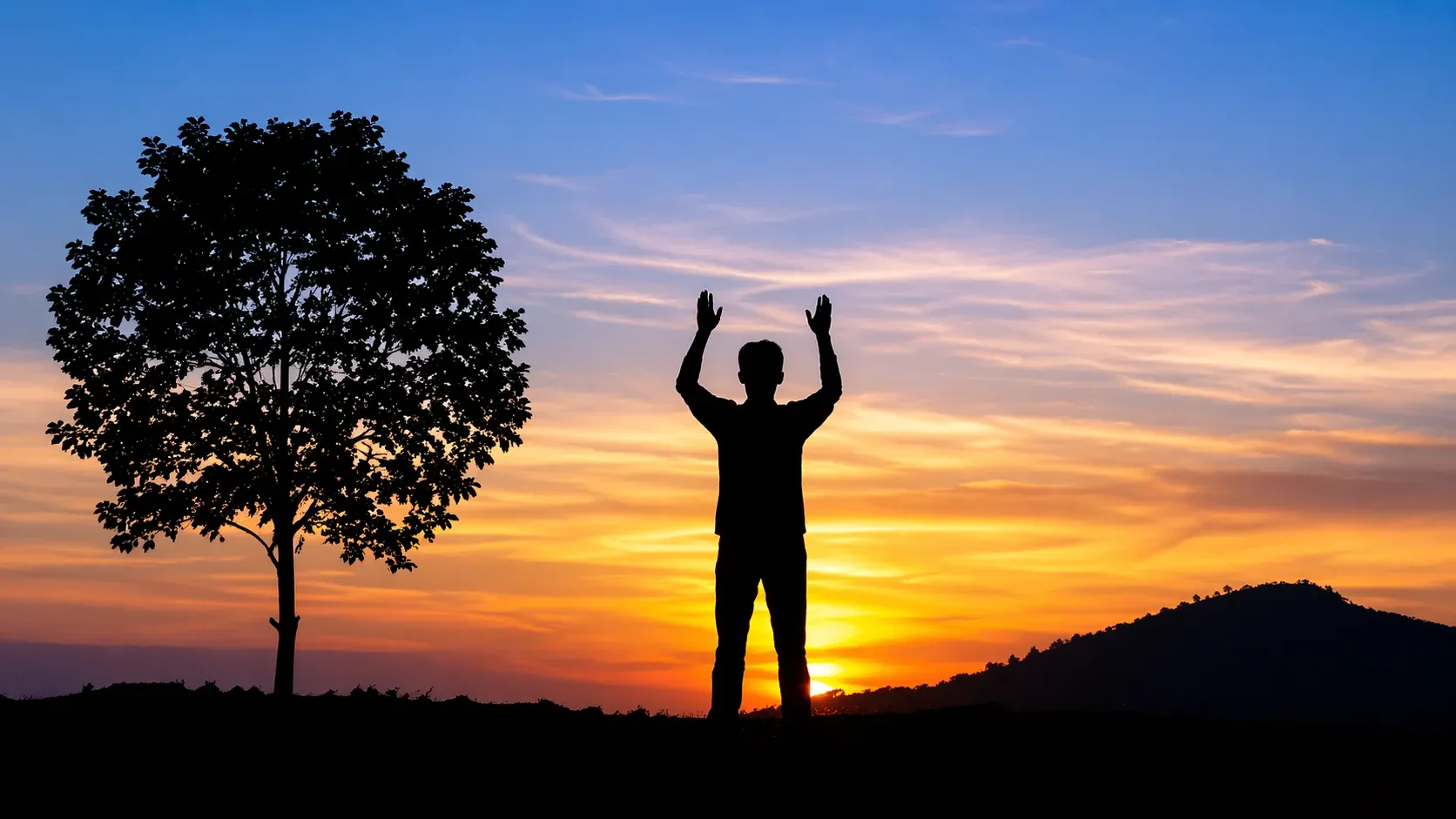 A silhouette of a person raising hands at sunset, symbolizing surrender, devotion, and connection with the Divine.