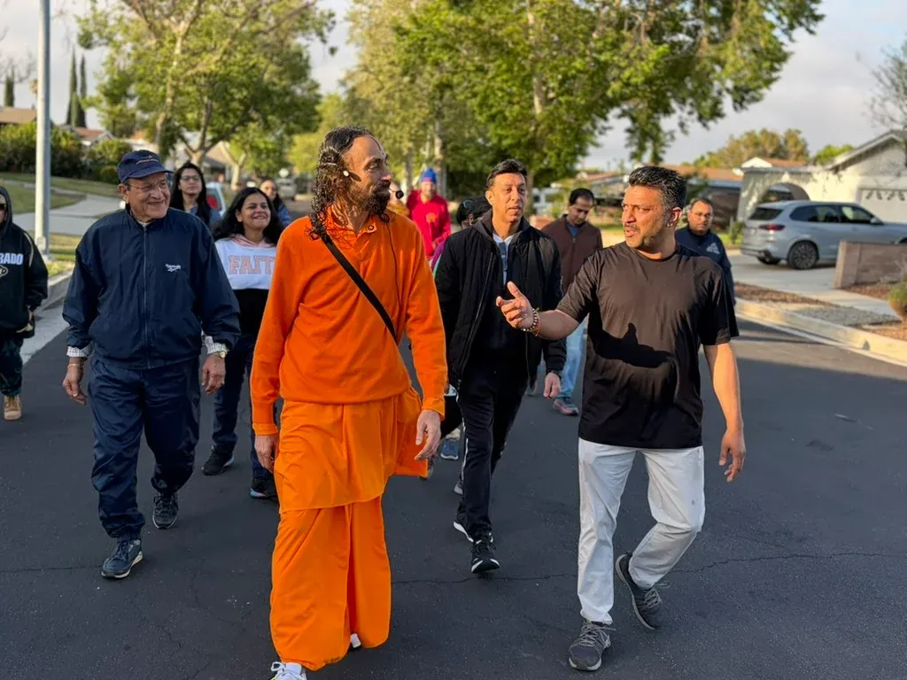Participants walking with Swamiji in a serene natural setting during a morning walk session.