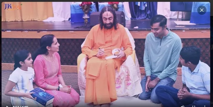 Swami Mukundananda seated with a family, including children and parents, during a devotional program and book signing.