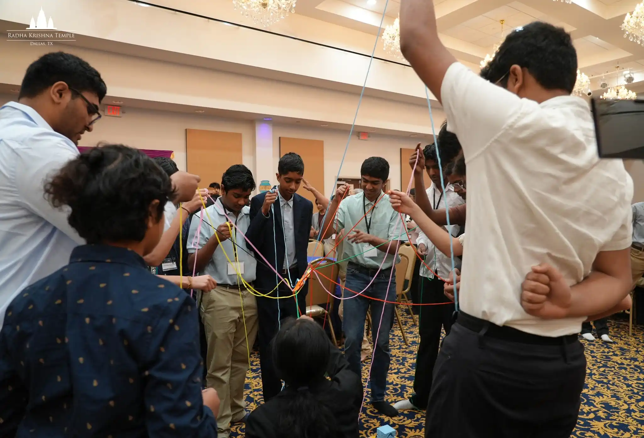 : Students hold colorful strings in a circle during a team-building activity at the 2026 Youth Leadership Workshop.