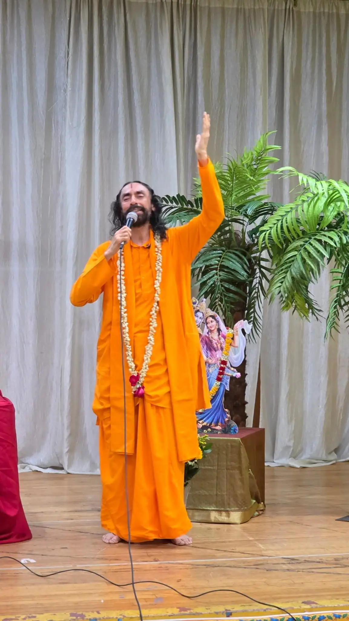 Swami Mukundananda speaking on stage with a microphone at the Connecticut Life Transformation Program.