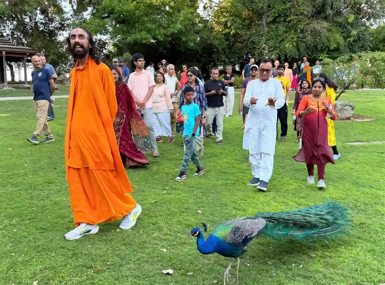 Swamiji walking during the morning Parikrama with devotees and a peacock