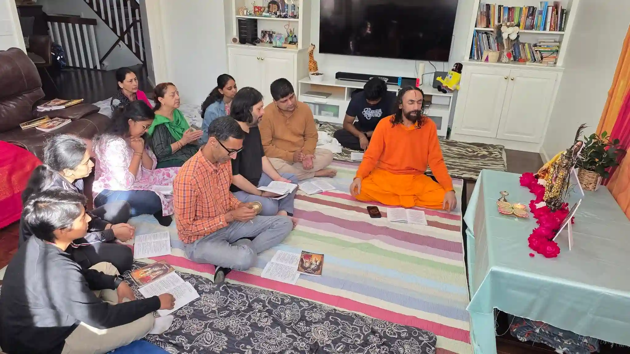 Swami Mukundananda seated with devotees during a home satsang in Connecticut.