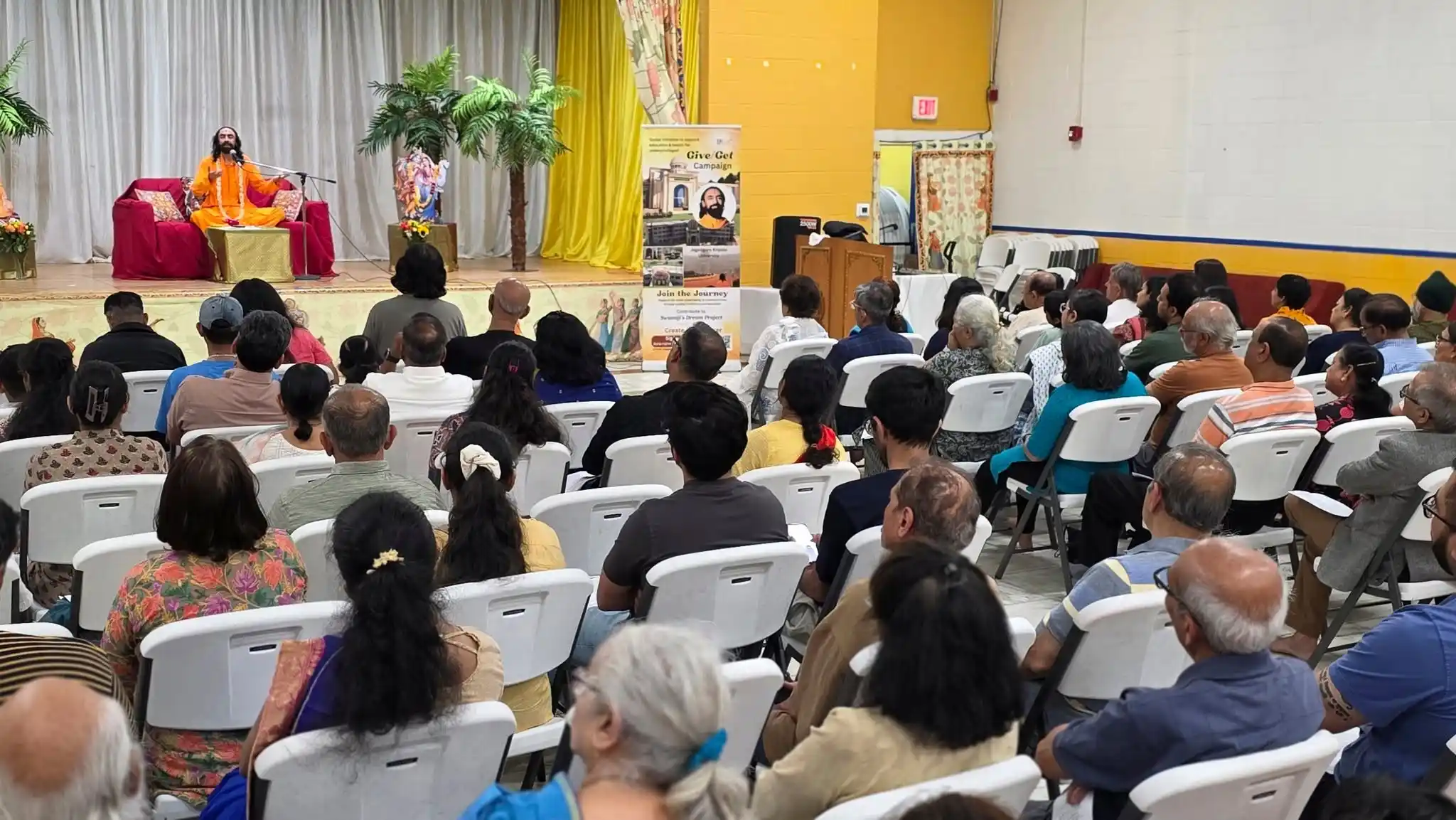 Audience seated in a hall listening to Swami Mukundananda speak on stage at the Connecticut Life Transformation Program.