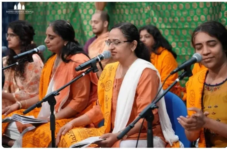 Women devotees singing kirtan with microphones during satsang at Radha Krishna Temple of Dallas